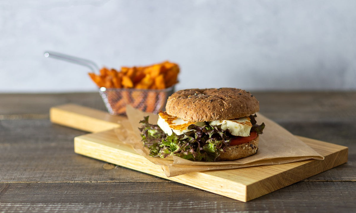 A burger with lettuce and tomato served with sweet potato fries.
