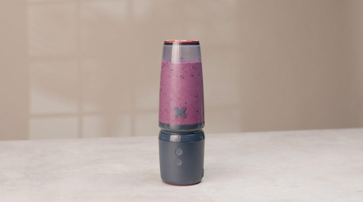 A blender with a purple smoothie on a countertop.