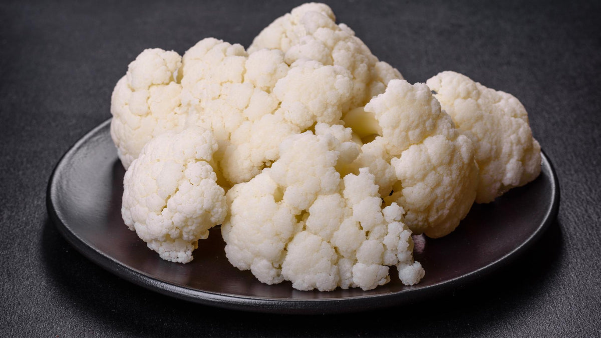 A serving of fresh cauliflower on a black plate.