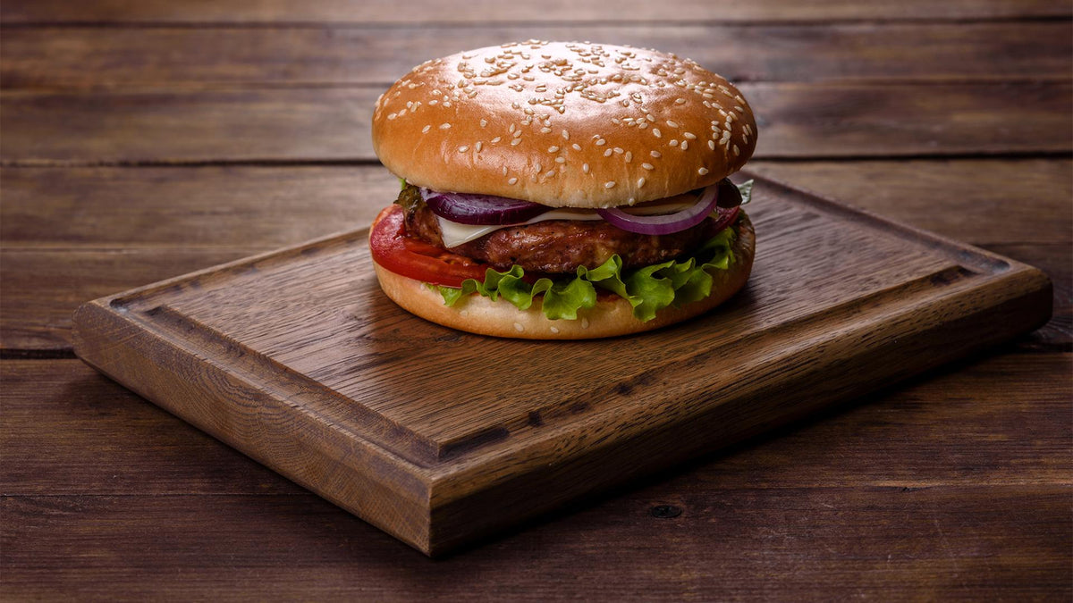 A delicious hamburger with sesame seed bun on a wooden board.
