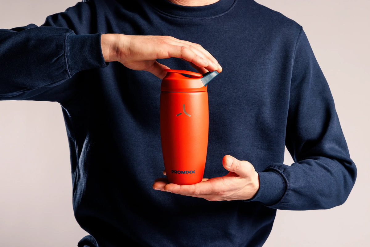 Hands opening the lid of a red PROMIXX Pursuit bottle