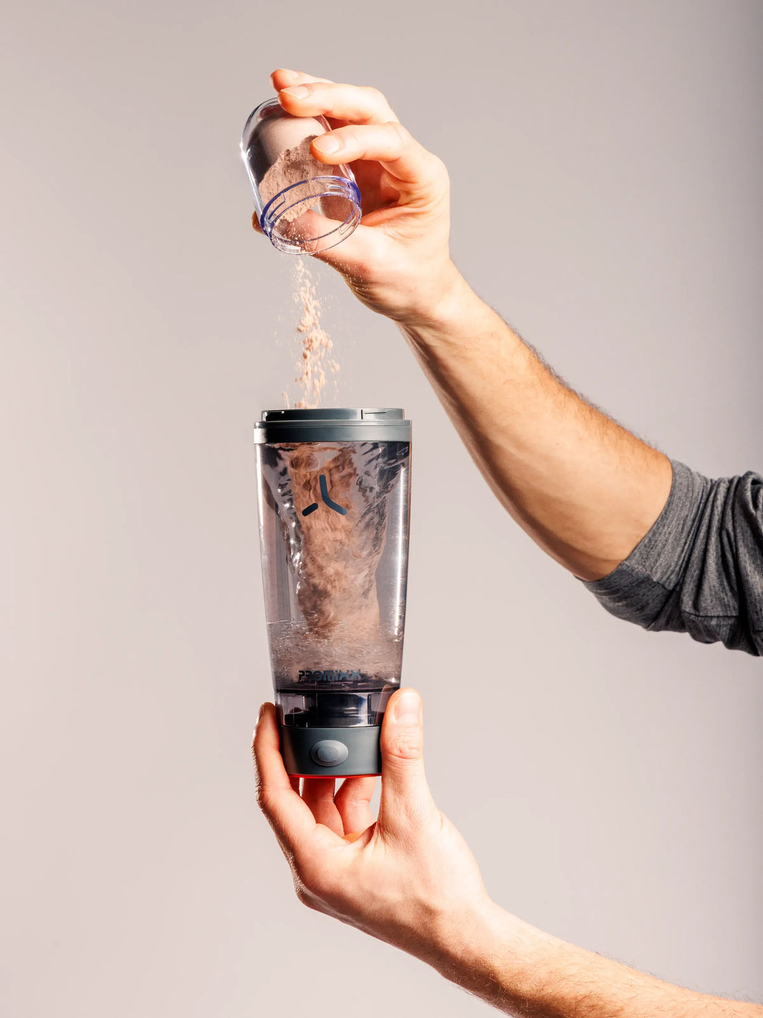 Protein powder being poured into a clear PROMIXX shaker bottle