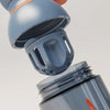 PROMIXX Ecozen Hybrid water bottle in Midnight Blue — close-up of the perforated dome mixing agitator lifting away from the bottle.