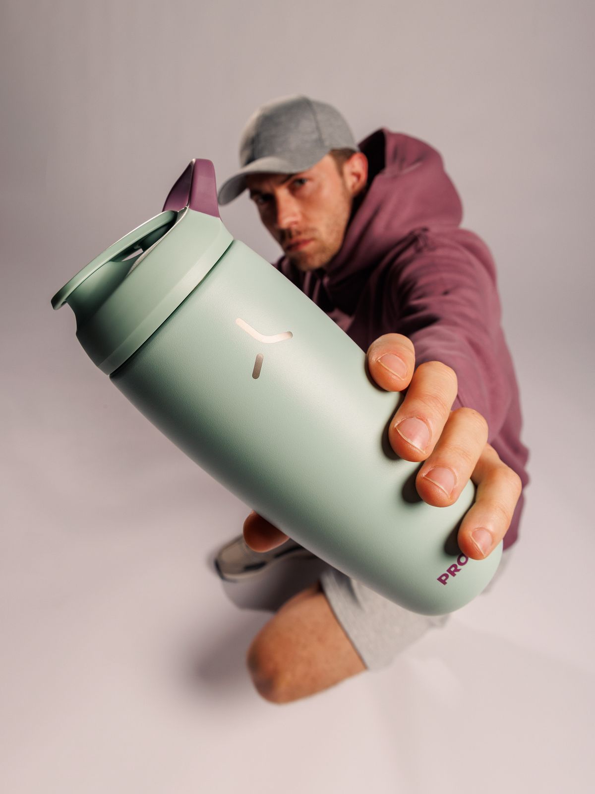 Pursuit shaker in Seagrass Green / Mulberry held by an athlete