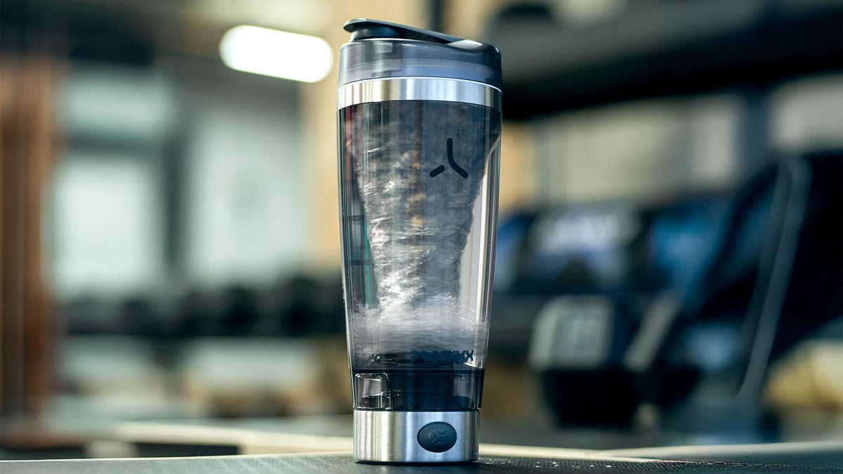 PROMiXX electric shaker mixing a protein shake on a gym counter